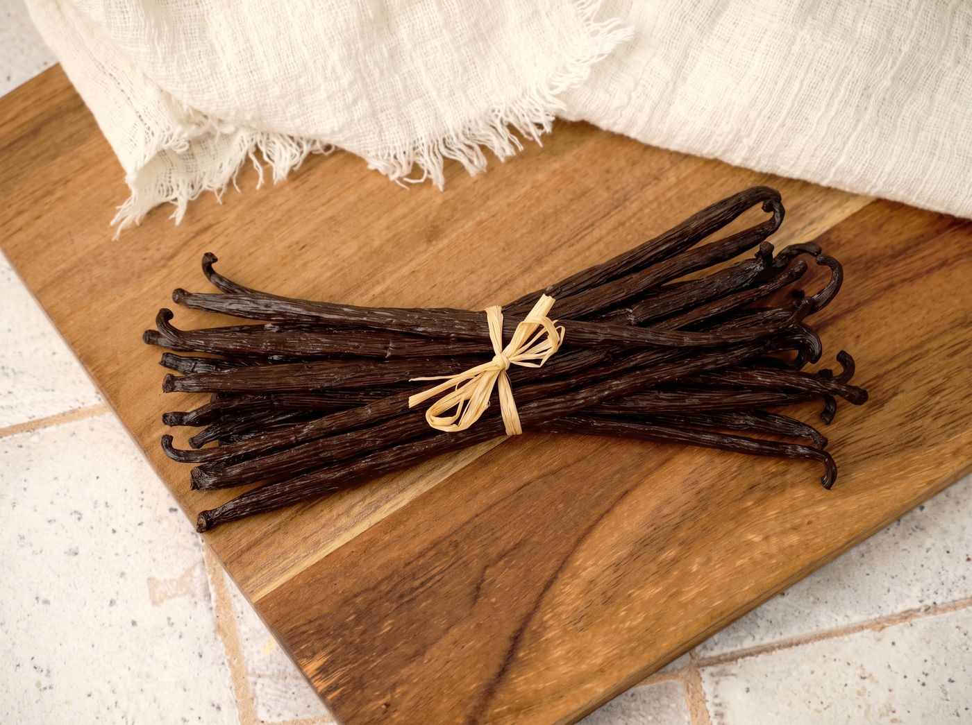 Bundle of Indonesian Vanilla Planifolia pods on a wooden board